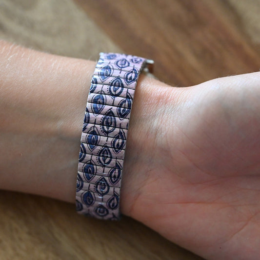 Stretcharmband mit blauem Blattmuster auf rosa Hintergrund, getragen am Handgelenk, auf Holzoberfläche