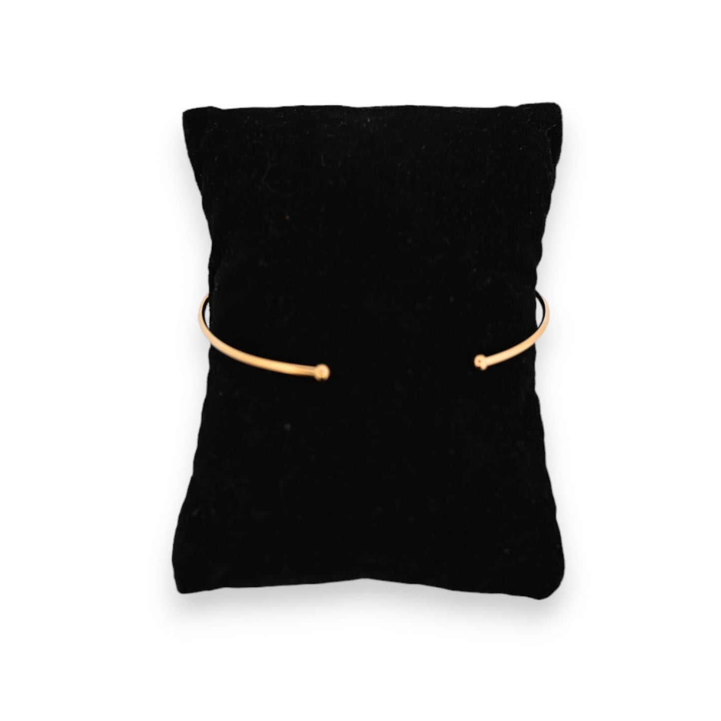 Goldener offener Armreif auf schwarzem Samtkissen, minimalistisches Design, elegantes Schmuckstück für Damen