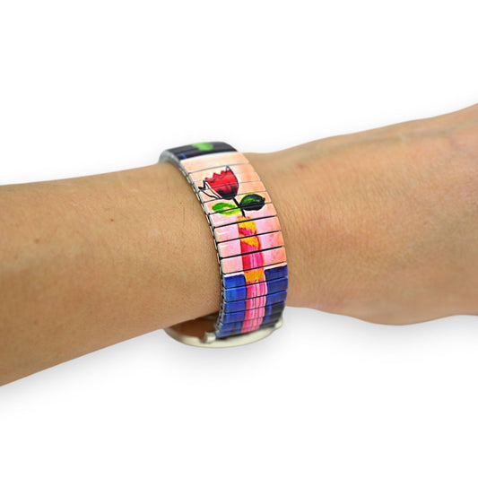 Bunte Armbanduhr mit elastischem Armband und Blumenmotiv, rote Tulpe auf rosa-blauem Hintergrund, am Handgelenk getragen