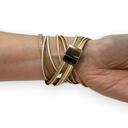 Mehrreihiges Lederarmband in Beige-Tönen mit Sternen-Muster und silbernem Verschluss am Handgelenk getragen