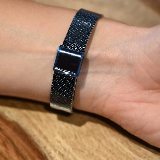 Elegante Armbanduhr mit dunkelblauem Mesh-Armband und schimmerndem Zifferblatt auf Handgelenk, auf Holzuntergrund