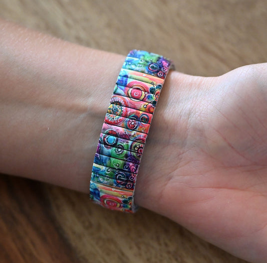 Bunte elastische Armbanduhr mit abstraktem Muster aus Kreisen und Linien in Blau, Rot, Grün und Pink am Handgelenk