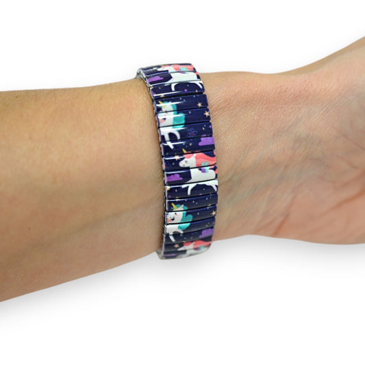 Dehnbares Armband mit buntem Einhorn-Motiv auf dunkelblauem Hintergrund mit Sternen, am Handgelenk getragen