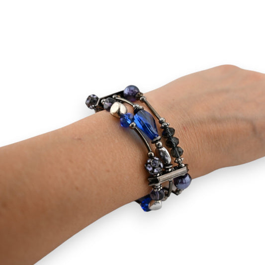 Mehrreihiges Armband mit blauen und silbernen Perlen, Kristallen und Metalldetails am Handgelenk einer Person