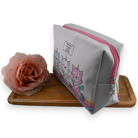 Toilettentasche mit Einhorn-Katzen-Motiv, rosa Reißverschluss und Stern-Anhänger, neben rosa Rose auf Holzbrett