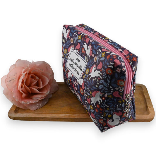 Bunte Einhorn-Kosmetiktasche mit Blumenmuster neben rosa Rose auf Holzbrett, Geschenkidee für Mädchen