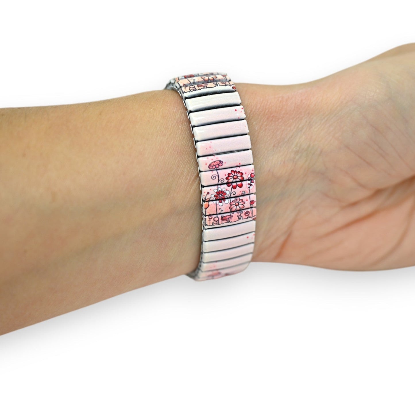 Elastisches Armband mit rosa Blumenmuster auf weißem Hintergrund, am Handgelenk getragen. Modisches Accessoire.