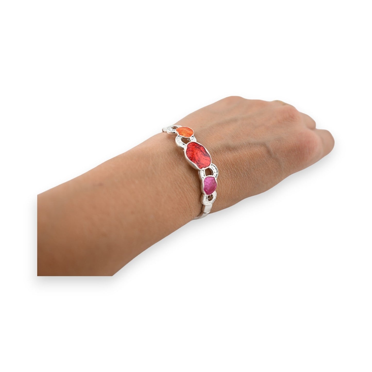 Elastisches Armband mit bunten Steinen in Orange, Rot und Pink auf silbernem Band, am Handgelenk getragen