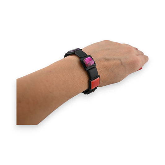 Elastisches Armband mit bunten quadratischen Elementen auf Handgelenk, modernes Design in Schwarz, Pink und Rot