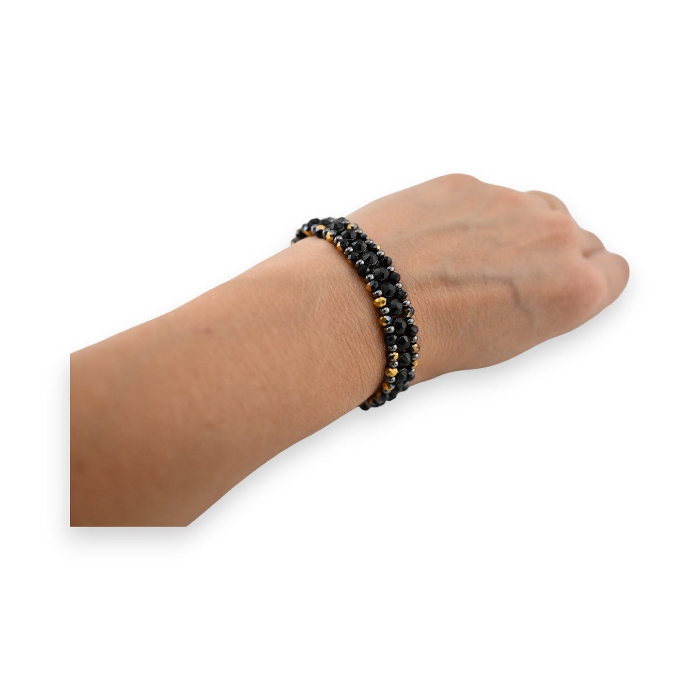 Elastisches Armband mit schwarzen und goldenen Perlen am Handgelenk, elegant und schimmernd auf heller Haut