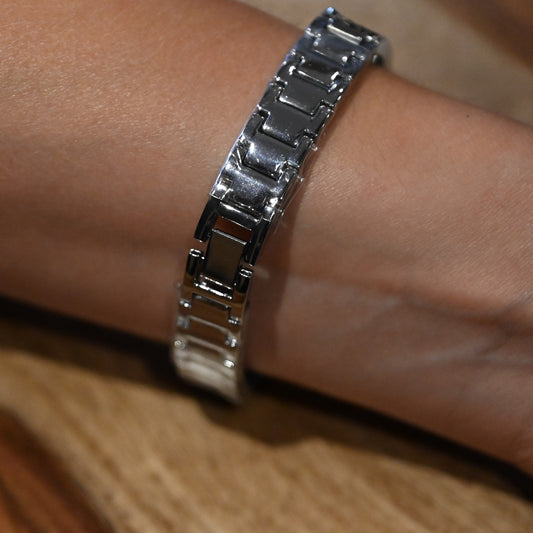 Silbernes Armband auf Handgelenk, metallisches Design mit rechteckigen Gliedern, eleganter Schmuck auf Holzuntergrund