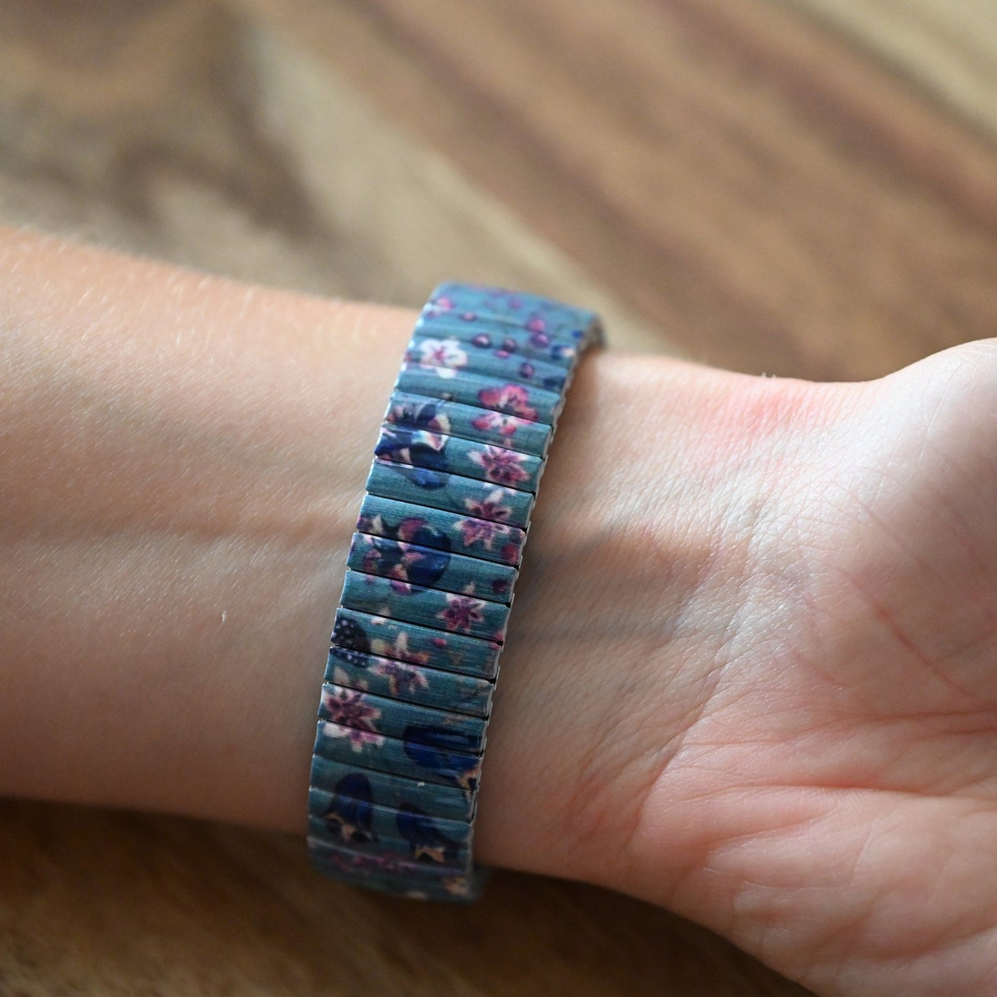 Armband mit blau-violettem Blumenmuster auf Handgelenk, elastisches Stretchband mit floralen Motiven
