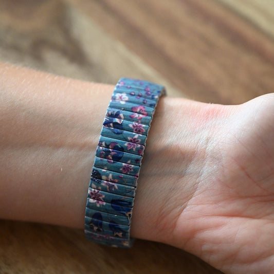 Armband mit blau-violettem Blumenmuster auf Handgelenk, elastisches Stretchband mit floralen Motiven