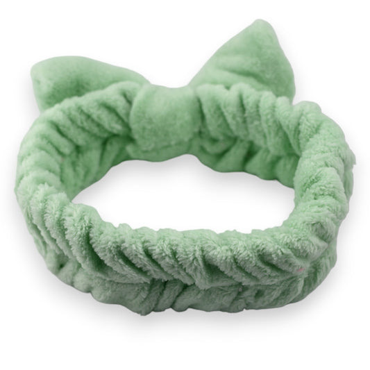 Weiches, mintgrünes Stirnband mit Schleife aus Plüsch für Makeup und Haarpflege, isoliert auf weißem Hintergrund