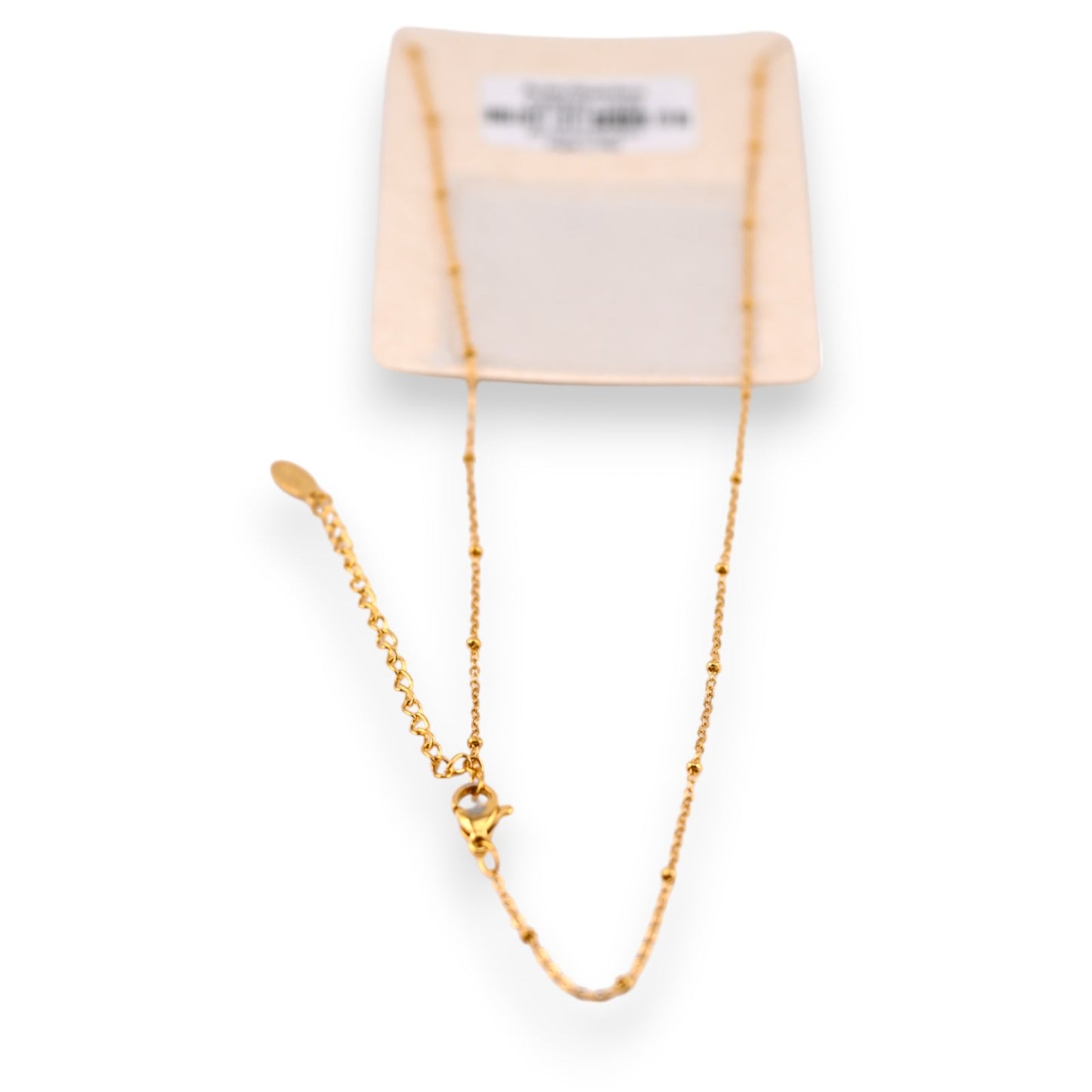 Filigrane vergoldete Stahlkette mit feinen Perlen auf zartrosa Verpackung, elegantes Schmuckstück für Damen