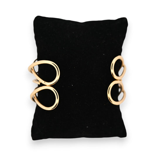 Goldenes Armband mit zwei kreisförmigen Elementen auf schwarzem Hintergrund, minimalistisches Design