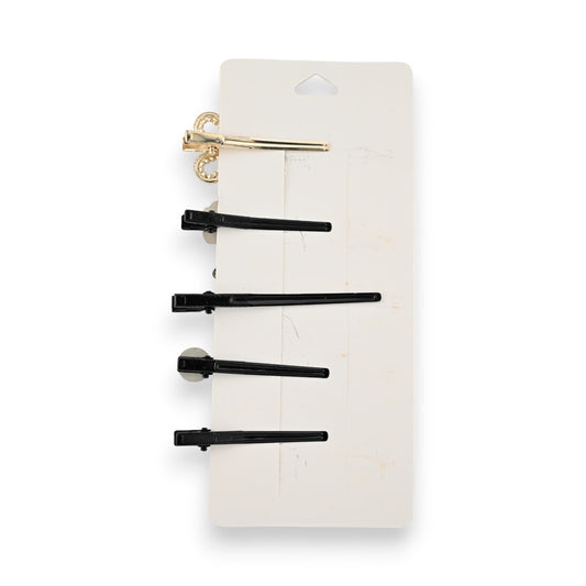 Set aus 5 Haarspangen: 1 goldene mit Verzierung und 4 schwarze in verschiedenen Größen auf weißer Verpackung