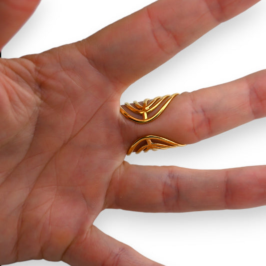 Goldener Ring aus geschwungenem Metall, getragen an einem Finger. Nahaufnahme der Hand zeigt das einzigartige Design.