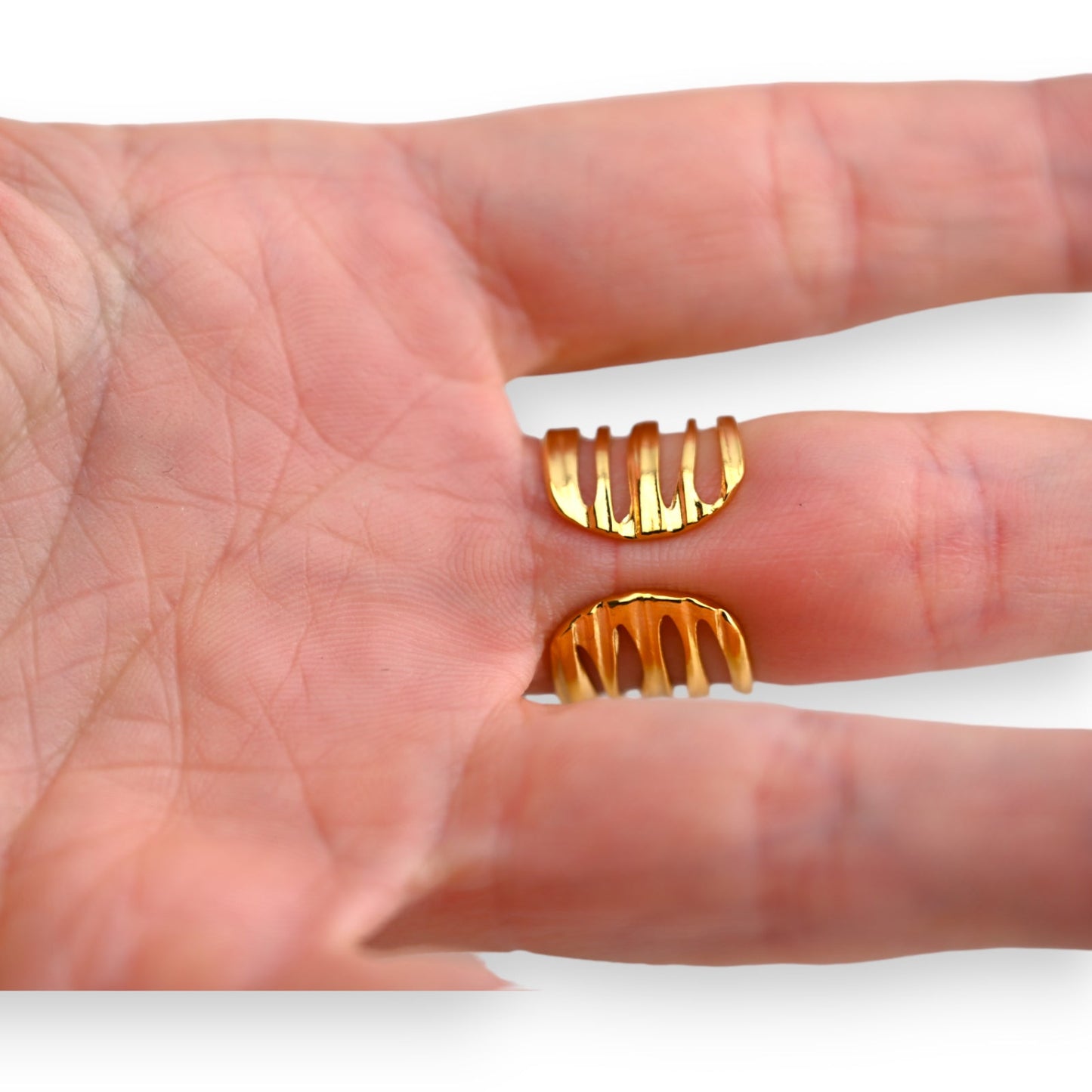 Goldener Stahlring mit gezacktem Design auf einer Hand. Zwei Ringe zeigen die Form und Größe des Schmuckstücks.