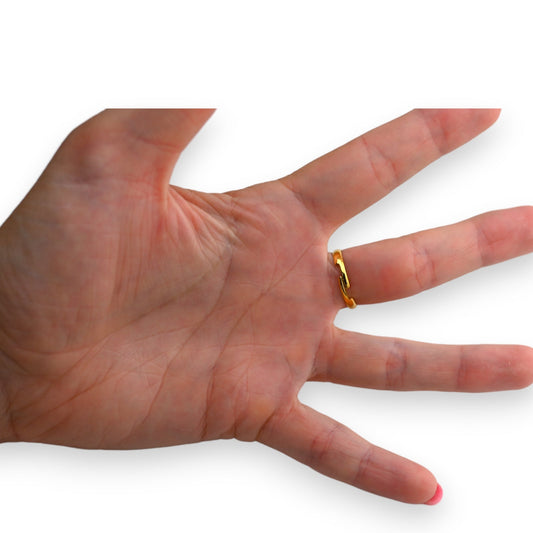 Goldener Stahlring mit Herz-Strass am Ringfinger einer ausgestreckten Hand, Nahaufnahme der Handfläche