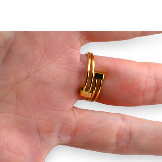 Goldener Stahlring mit Knotendesign auf Fingerspitze. Moderner Schmuck mit verschlungenen Linien und einem rechteckigen El...