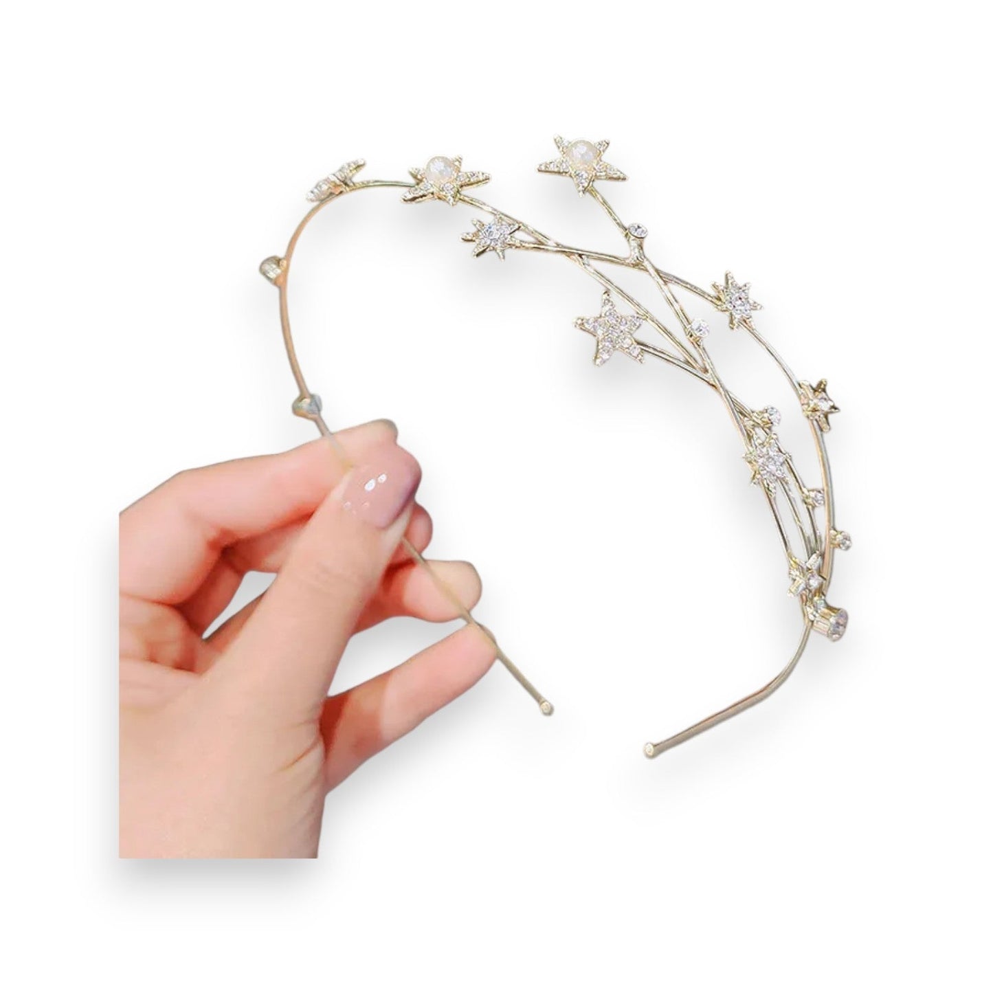 Goldener Haarreif mit funkelnden Sternen aus Strasssteinen, gehalten von einer Hand mit manikürten Nägeln