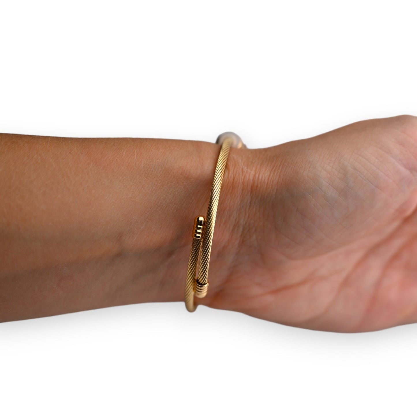 Goldenes Kabelarmband am Handgelenk, minimalistisches Design mit subtilen Verzierungen, eleganter Schmuck