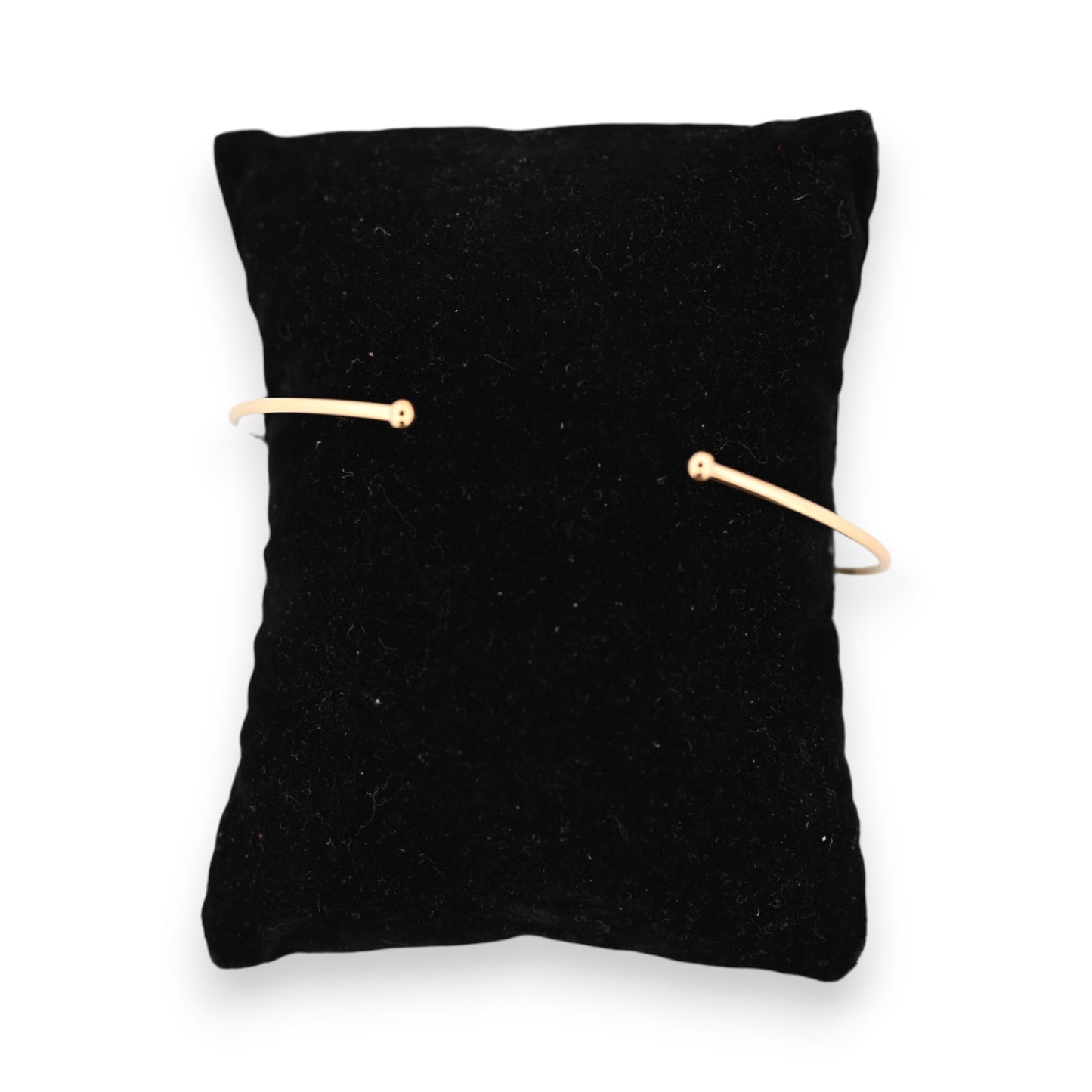 Goldenes Armreif auf schwarzem Samtkissen, minimalistisches Design mit offenen Enden, elegantes Accessoire