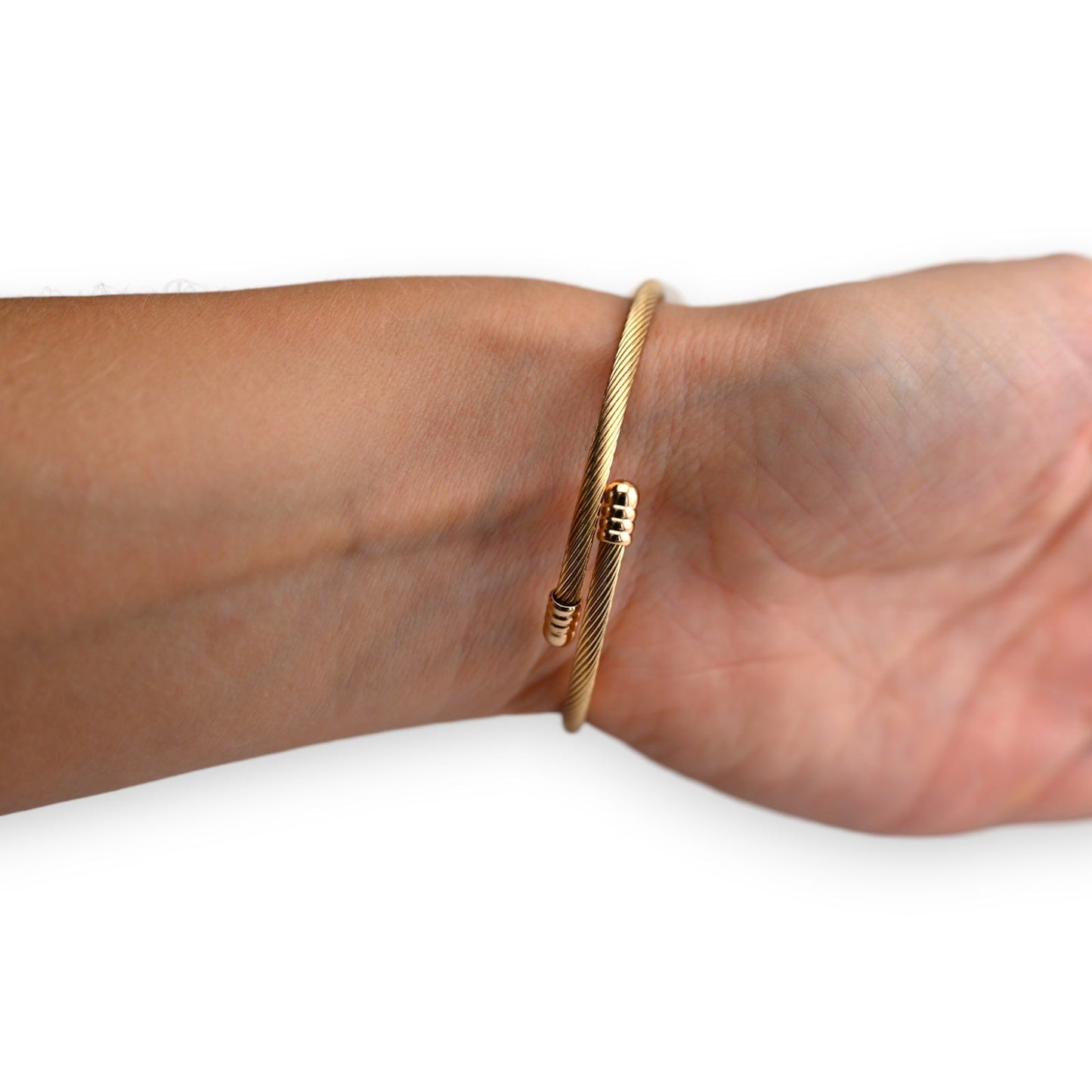 Elegantes goldenes Kabelarmband mit feiner Textur, am Handgelenk getragen. Minimalistisches Design mit subtilen Details.