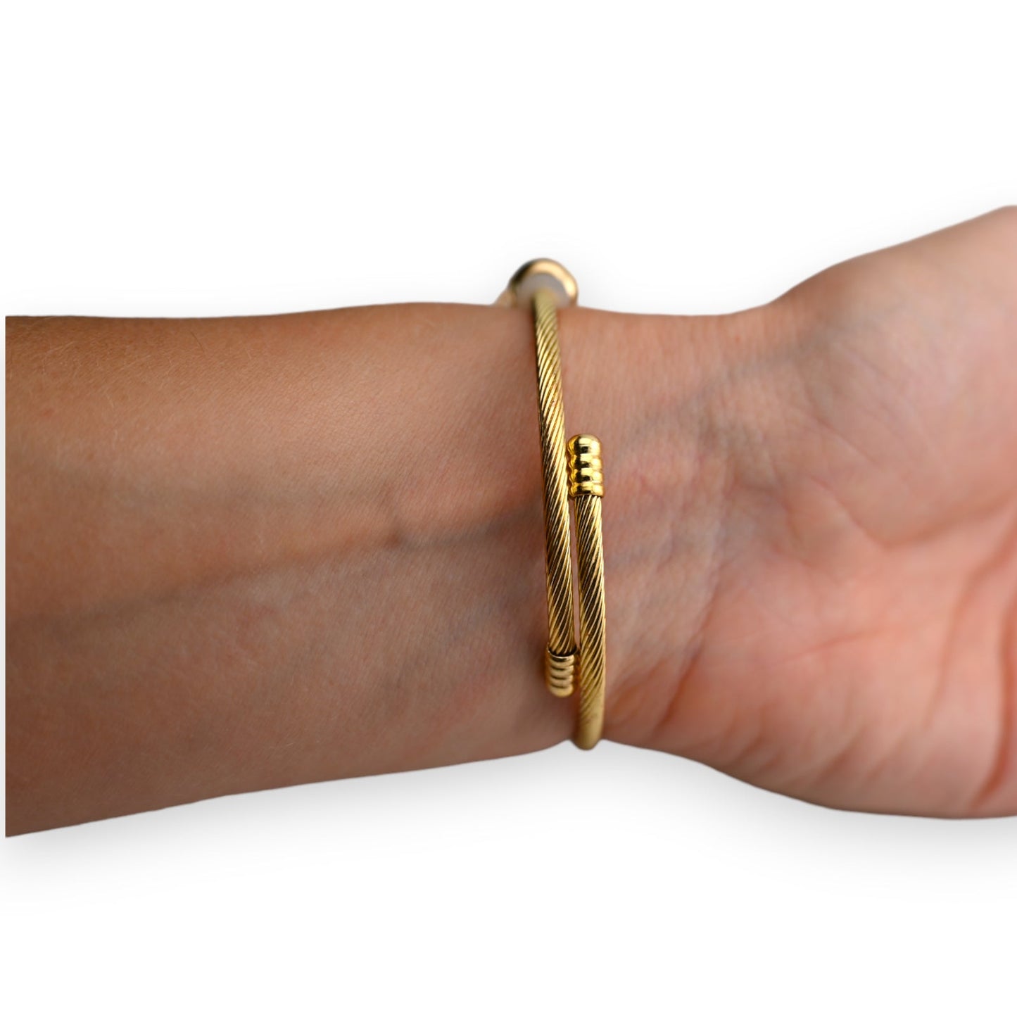 Goldenes Armreif mit gedrehtem Muster und Verschluss, auf Handgelenk getragen. Elegantes Schmuckstück für Damen.