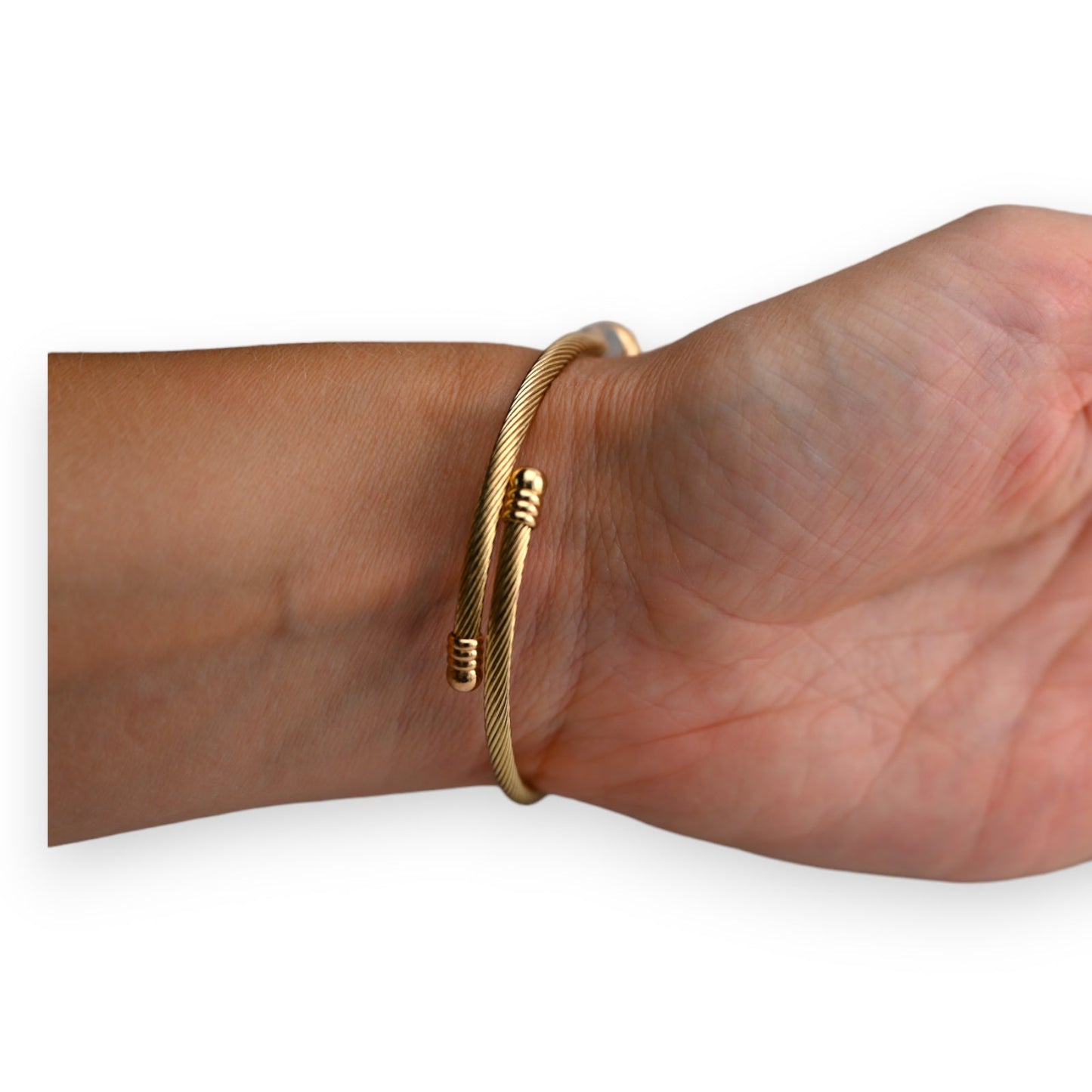 Goldenes Armreif mit geriffelter Oberfläche und offenen Enden, am Handgelenk getragen, minimalistisches Design