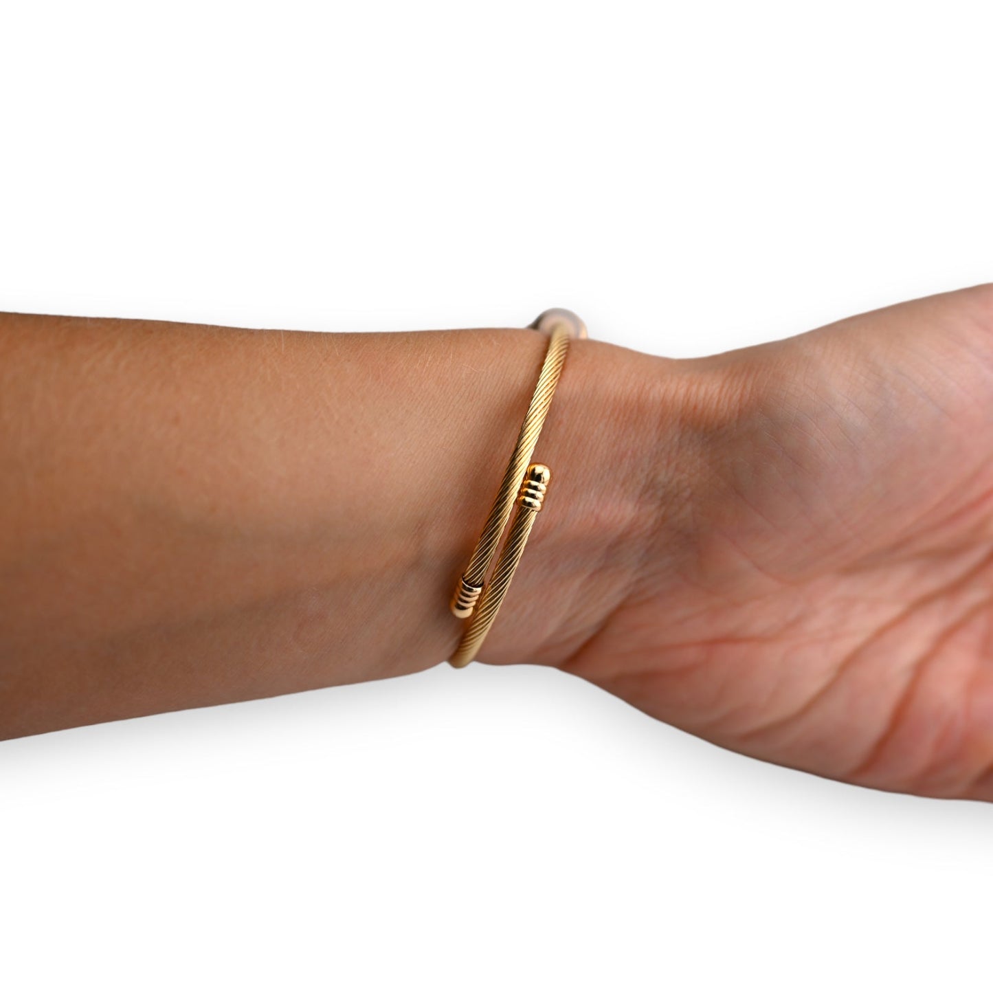 Goldenes Armreif mit feiner Drahtspirale und dezenten Akzenten, elegant am Handgelenk getragen