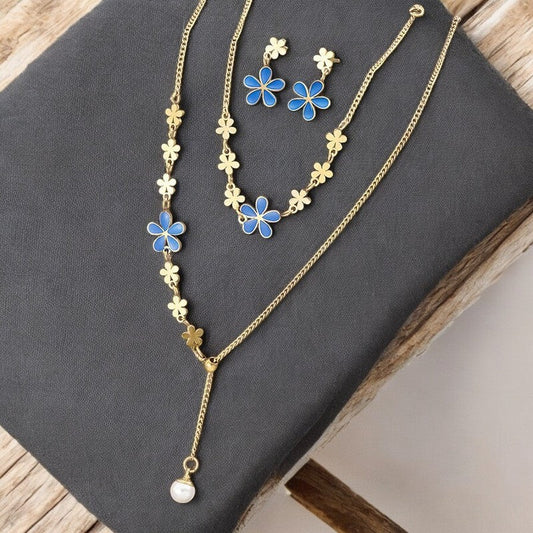 Goldenes Schmuckset mit blauen Blumen: lange Halskette, kurze Halskette und Ohrringe auf grauem Hintergrund