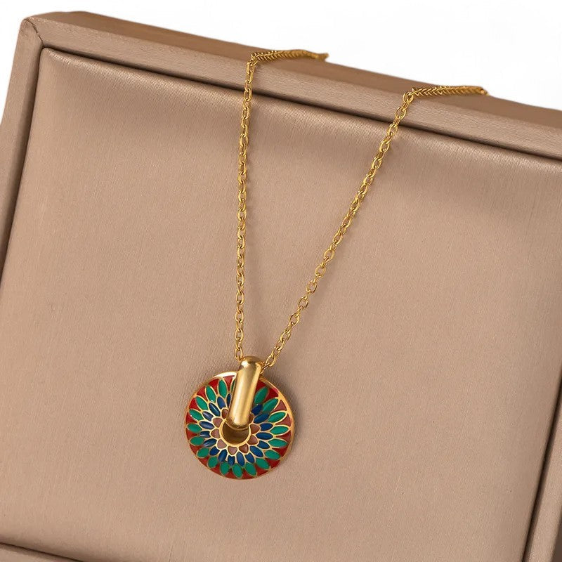 Goldene Halskette mit buntem Mandala-Anhänger auf beigem Schmuckkästchen, filigrane Kette und detailreiches Medaillon