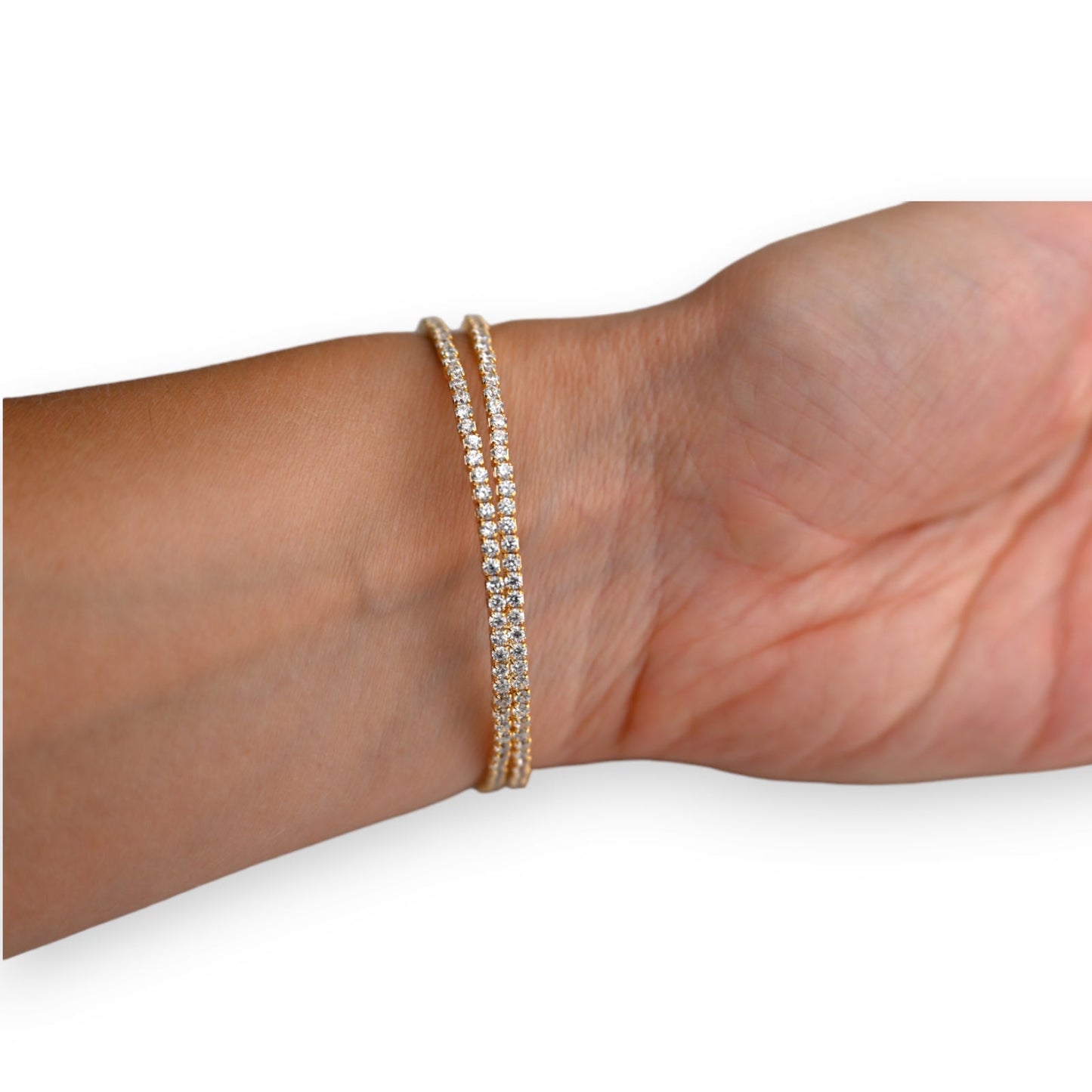 Elegantes mehrreihiges Armband aus goldenem Stahl mit funkelnden Kristallen am Handgelenk einer Person