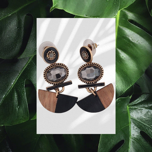 Elegante Ohrringe mit Holz, Stein und vergoldetem Metall. Geometrisches Design mit Halbkreisen auf grünem Blätterhintergrund