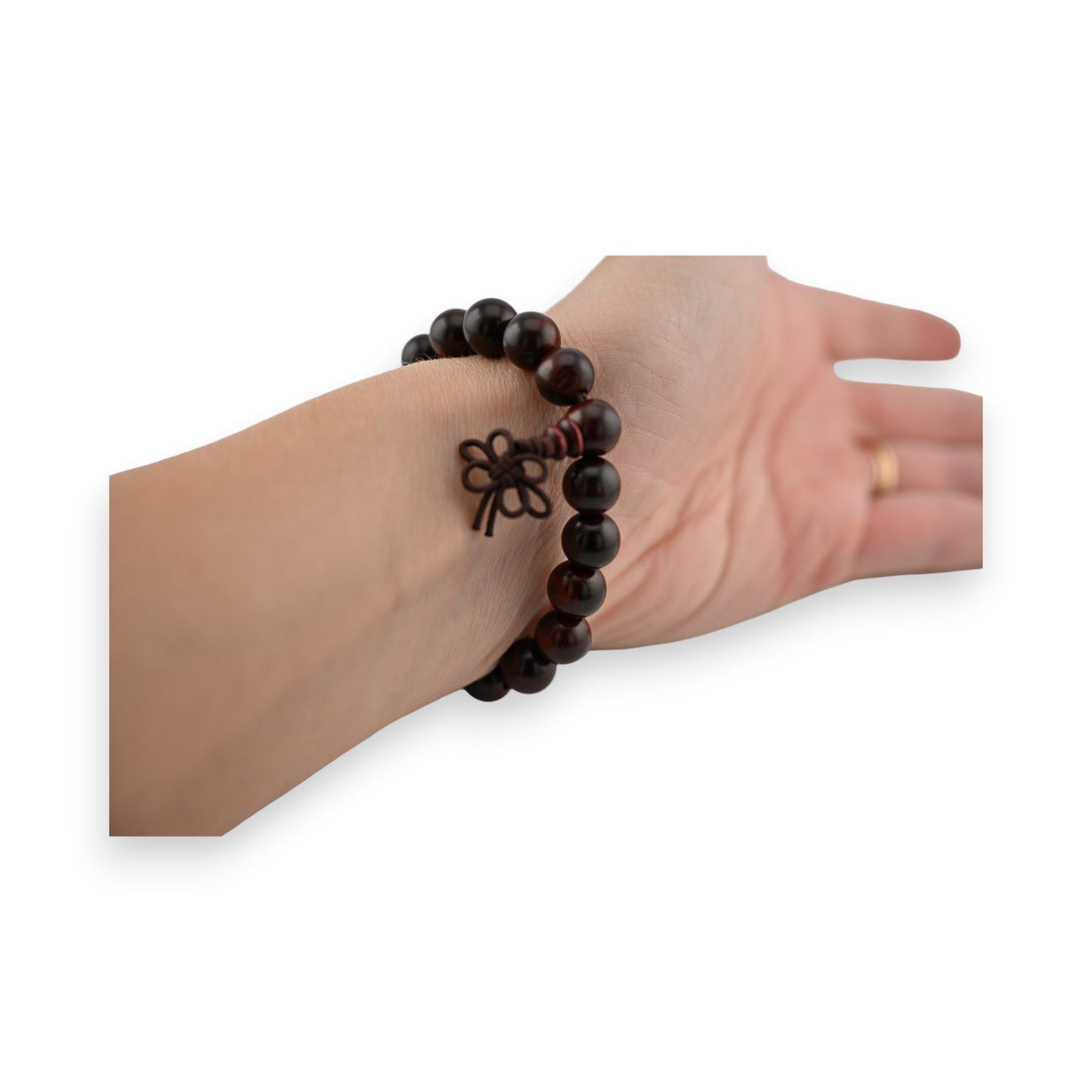 Elastisches Armband mit dunklen Holzperlen, Blumen-Tattoo am Handgelenk, goldener Ring am Finger sichtbar