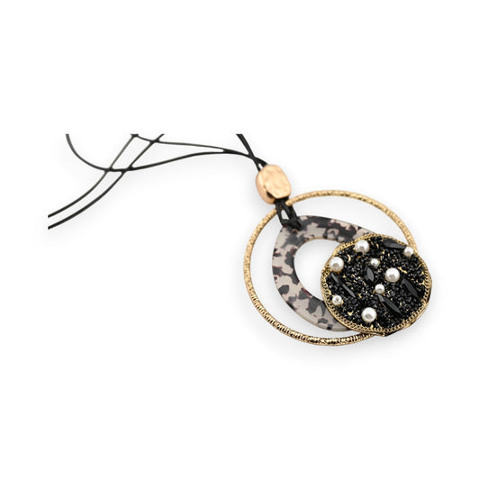 Lange Halskette mit rundem Anhänger, goldener Ring und schwarzem Medaillon mit Perlen, auf Leopardenmuster-Hintergrund