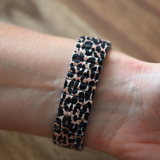 Armband mit Leopardenmuster in Schwarz und Rosa auf einem Handgelenk, elastisches Design mit modischem Tierdruck