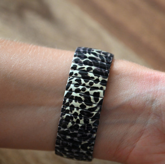 Armband mit Leopardenmuster auf Handgelenk, schwarz-weiße Tierdruck-Optik auf elastischem Schmuckband