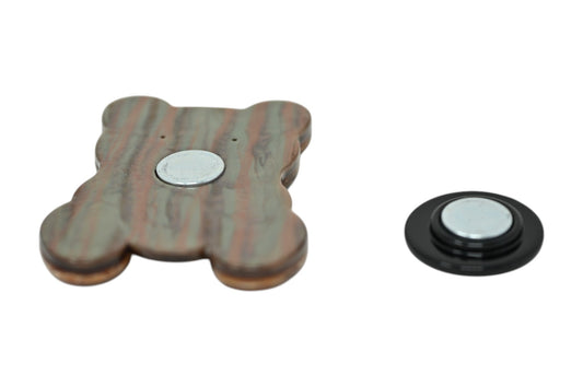 Magnetische Brosche in Teddybärform aus marmoriertem Kunstharz und separater schwarzer Magnethalter auf weißem Hintergrund