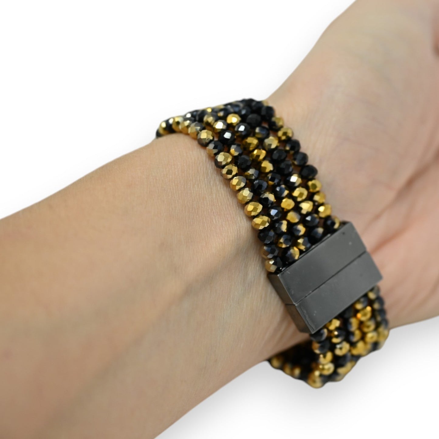 Mehrreihiges Armband mit goldenen und schwarzen Perlen, eleganter Magnetverschluss, am Handgelenk getragen