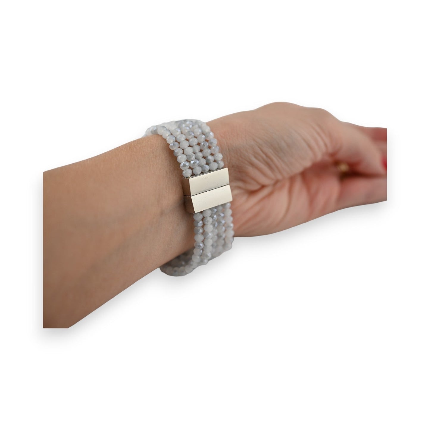 Mehrreihiges Modeschmuck-Armband mit grauen Perlen und silberfarbenem Magnetverschluss am Handgelenk einer Frau