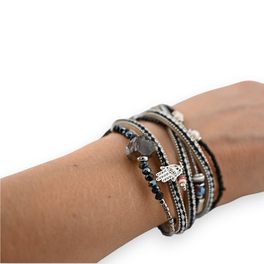 Mehrreihiges schwarzes Armband mit Kristallen, Perlen und Hamsa-Anhänger an einem Handgelenk auf weißem Hintergrund