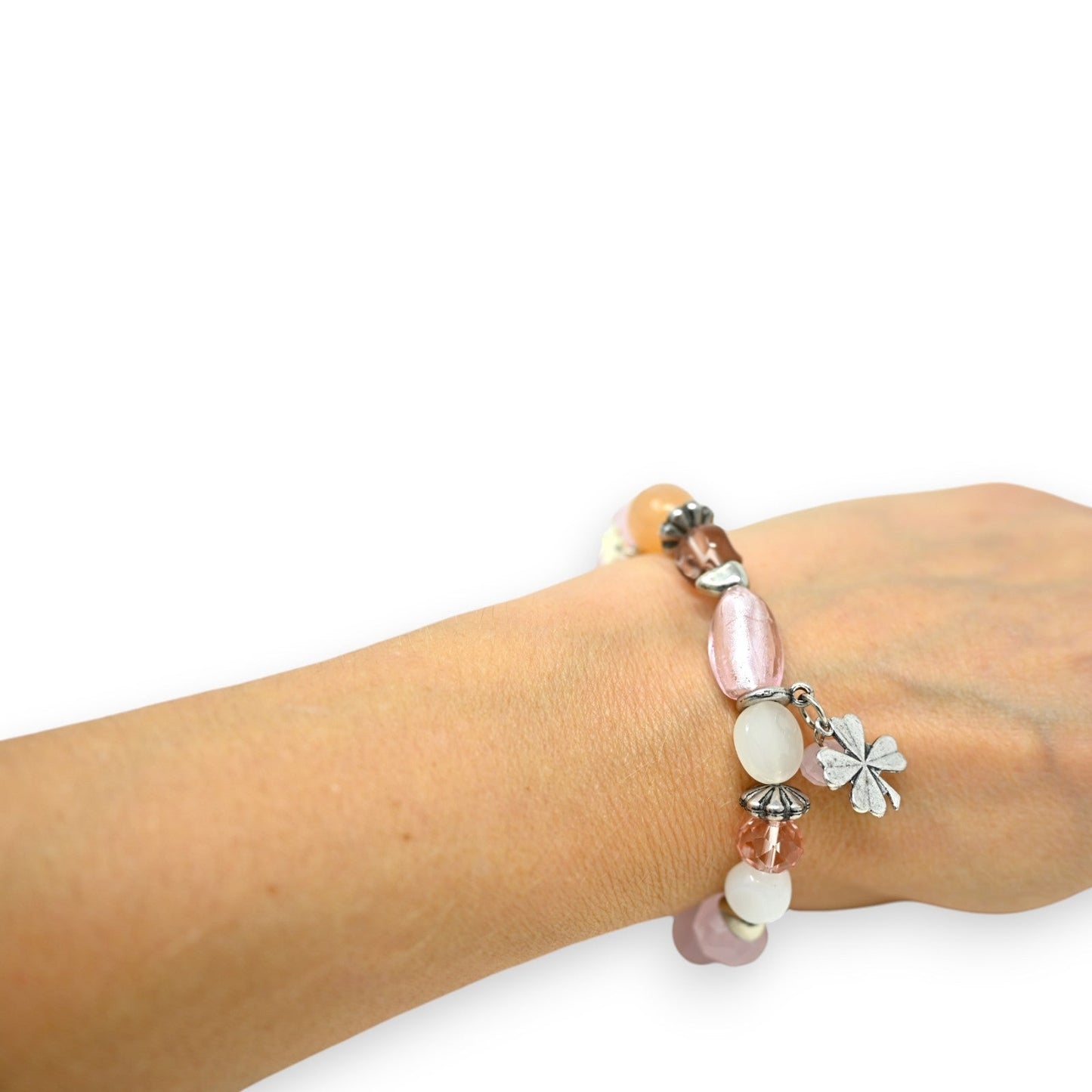 Elastisches Modeschmuck-Armband mit rosa und weißen Glasperlen, Silberanhängern und Kleeblatt-Charm am Handgelenk