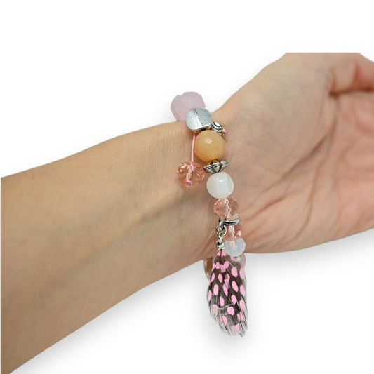 Elastisches Armband mit rosa und weißen Glasperlen, Silberanhängern und einer rosa-schwarz gepunkteten Feder