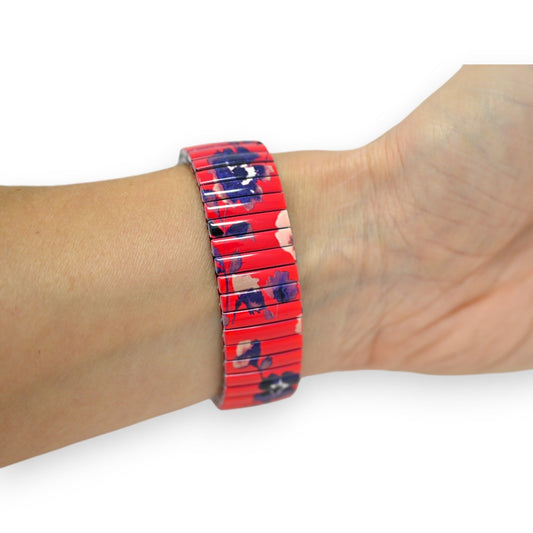 Rotes elastisches Armband mit Blumenmuster auf einem Handgelenk. Stilvolle Accessoire mit floralem Design auf rotem Grund.