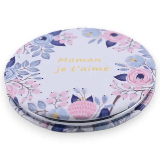 Runder Taschenspiegel mit floraler Dekoration und französischer Aufschrift 'Maman je t'aime' in Gold auf pastellfarbenem G...