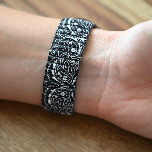 Armband mit schwarz-weißem Paisley-Muster auf Handgelenk, elastisches Design mit detaillierten Ornamenten