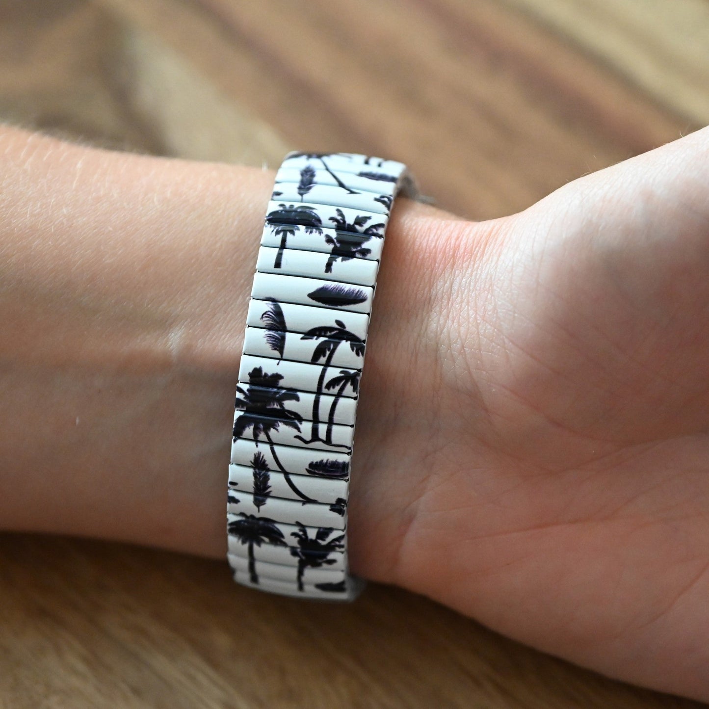Armband mit schwarz-weißem Palmenmuster auf Handgelenk, tropisches Design auf elastischem Band